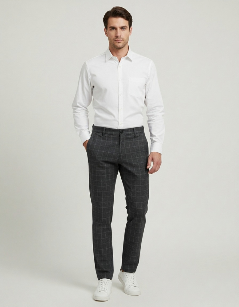 Muškarac u beloj košulji i kariranim slim fit pantalonama. Muškarac u beloj košulji i kariranim slim fit pantalonama.