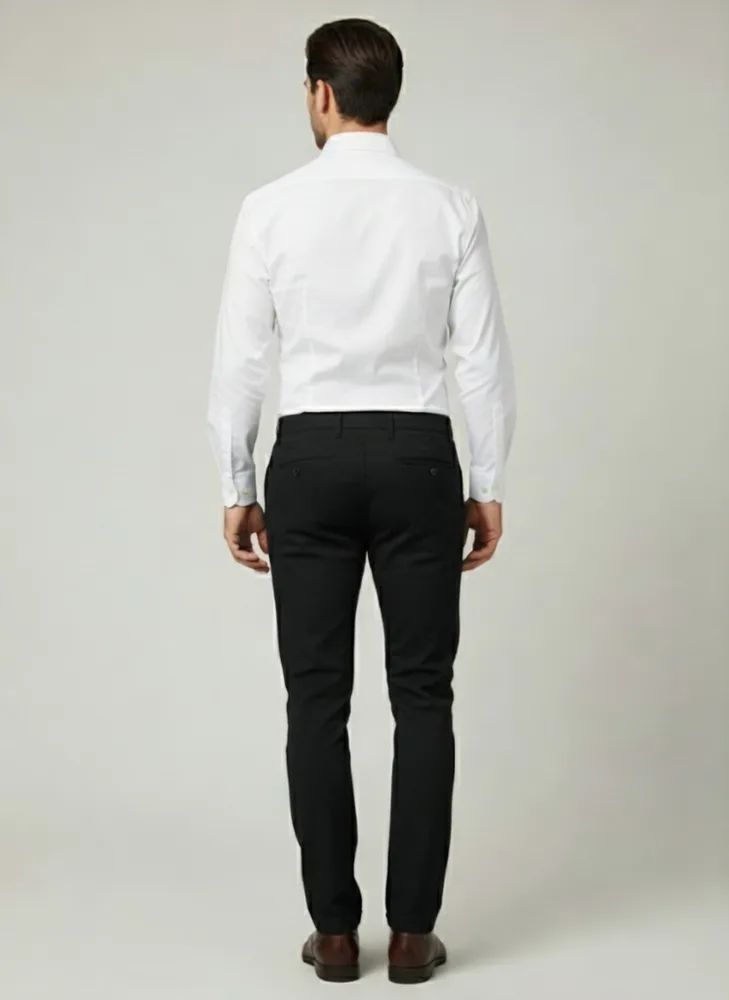 Pozadina: Muškarac nosi elegantne muške pantalone sa teksturom, regular fit, crne boje, sa belom košuljom. Pozadina: Muškarac nosi elegantne muške pantalone sa teksturom, regular fit, crne boje, sa belom košuljom.