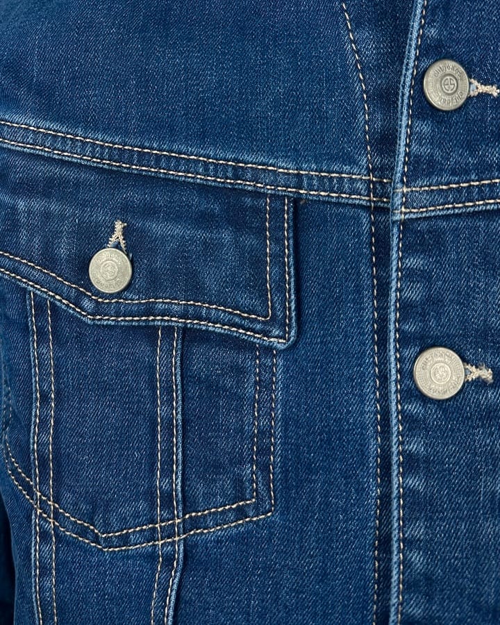 Detalj teksas jakne: džep, dugmad i štepovi.