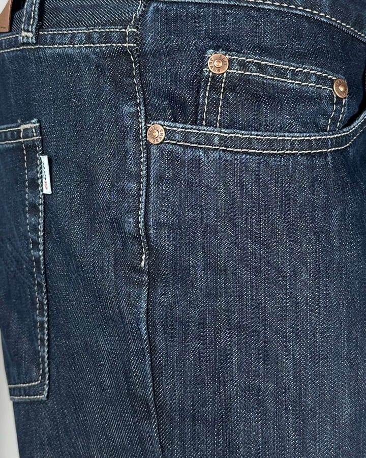 Detaljan prikaz regular fit farmerica za visoke sa produženom nogavicom, tamni teksas sa štepovima. Detaljan prikaz regular fit farmerica za visoke sa produženom nogavicom, tamni teksas sa štepovima.