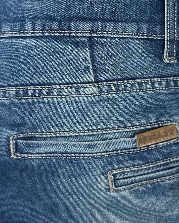 Detalj elegantnih muških termo pantalona za zimu, svetloplavi džins sa štepovima i etiketom.