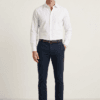Muškarac nosi elegantnu belu blago strukiranu košulju marke ELIT u kombinaciji sa crnim pantalonama i braon kaišem. elegantna bela muška košulja.