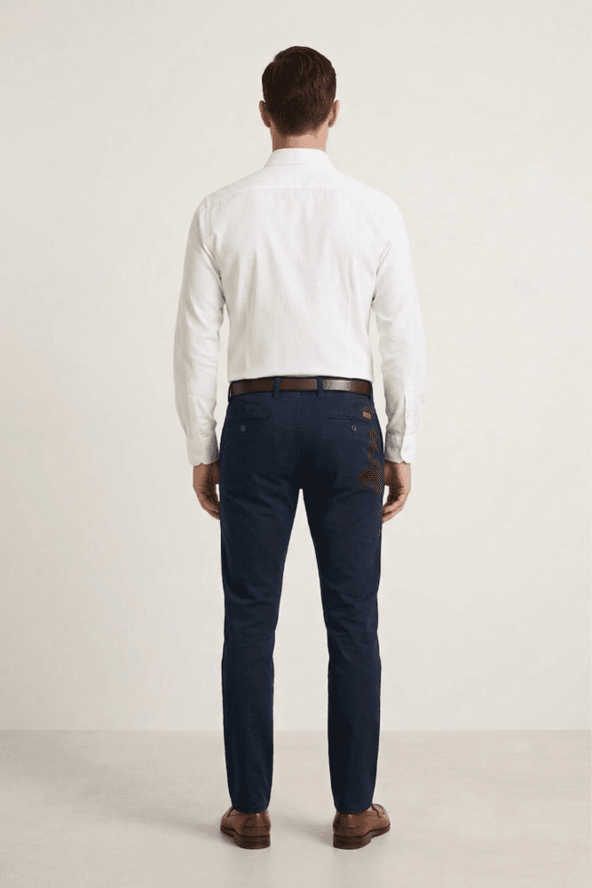 Muškarac nosi elegantnu belu blago strukiranu košulju marke ELIT u kombinaciji sa crnim pantalonama i braon kaišem.